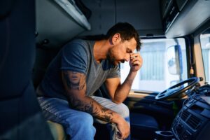 an exhausted long-haul trucker sitting in his cab