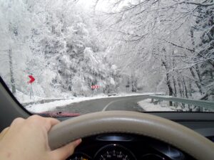 Person with hand on steering wheel driving in snow